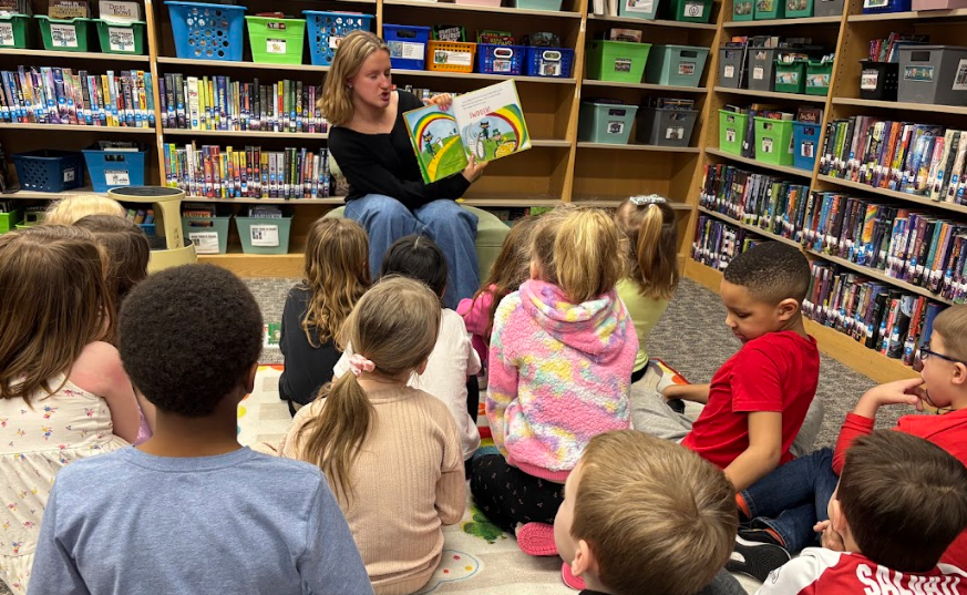 student sitting in front of younger students while reading
