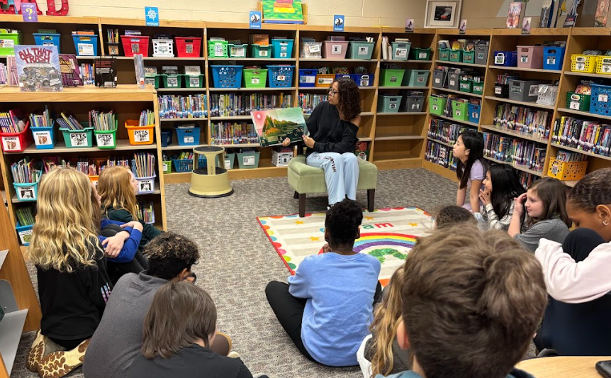 student sitting in front of younger students while reading