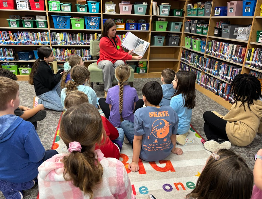 student sitting in front of younger students while reading
