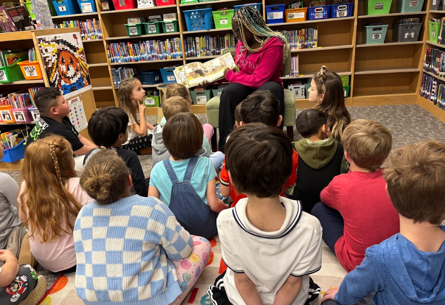 student sitting in front of younger students while reading