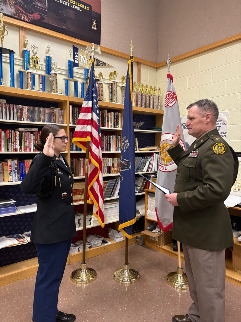 students holding hand up next to flag