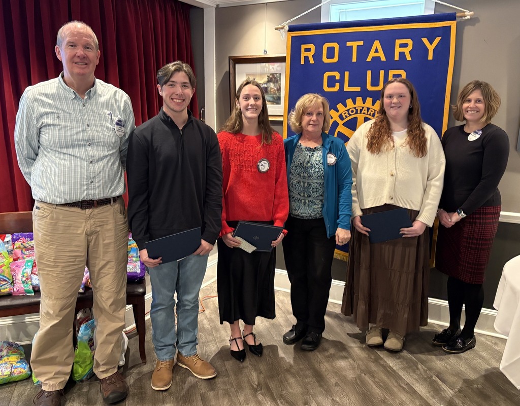 students standing in fornt of rotary club sign