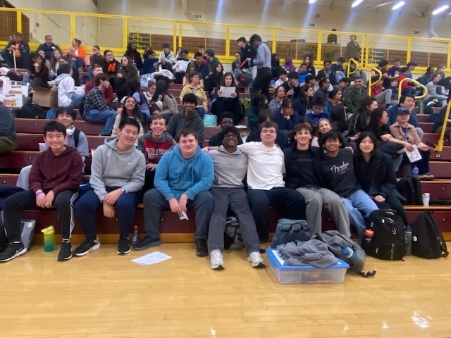 group of students sitting on  bleachr smiling at camera