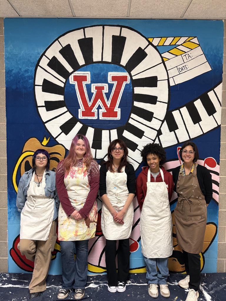 students with mural they created behind them