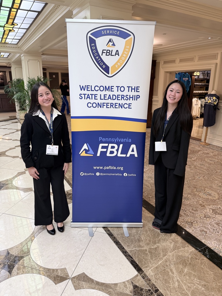 students in suits standing next to FBLA sign