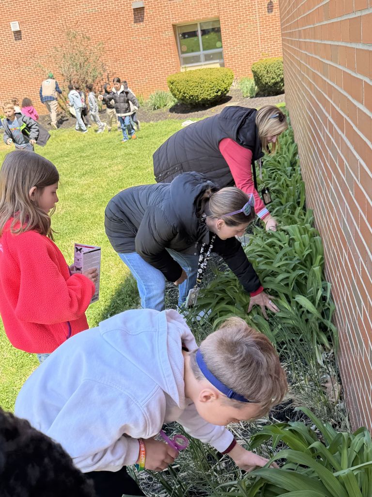 student and teachers touchingg the plants outside