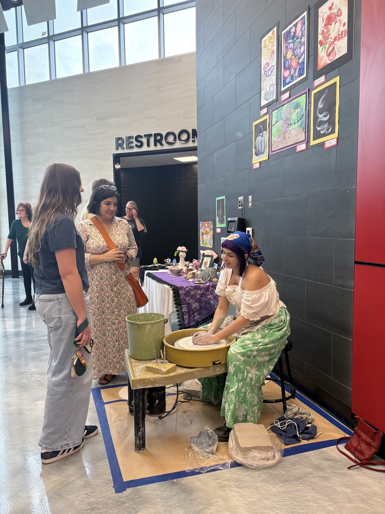 student creating pottery while people watch