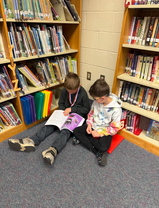 students reading book together in corner of library