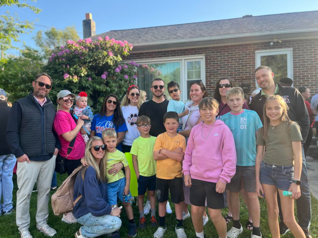 group of people standing outside the front of the house in t he grass