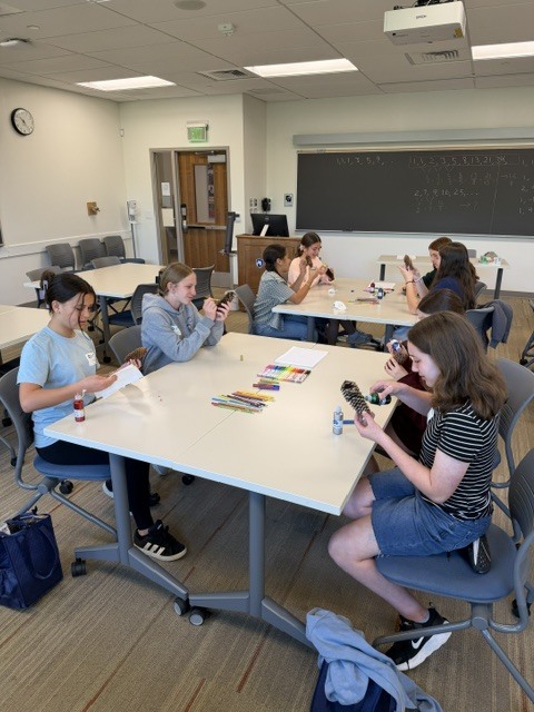 4 students sitting around a table doing craft
