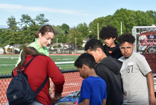 girl helping kids out with activity on table