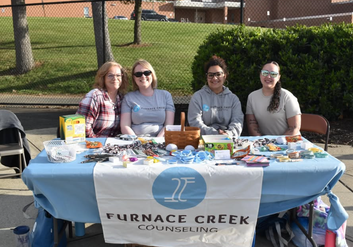 four women sitting at a table with a sign that says furnace creek counseling