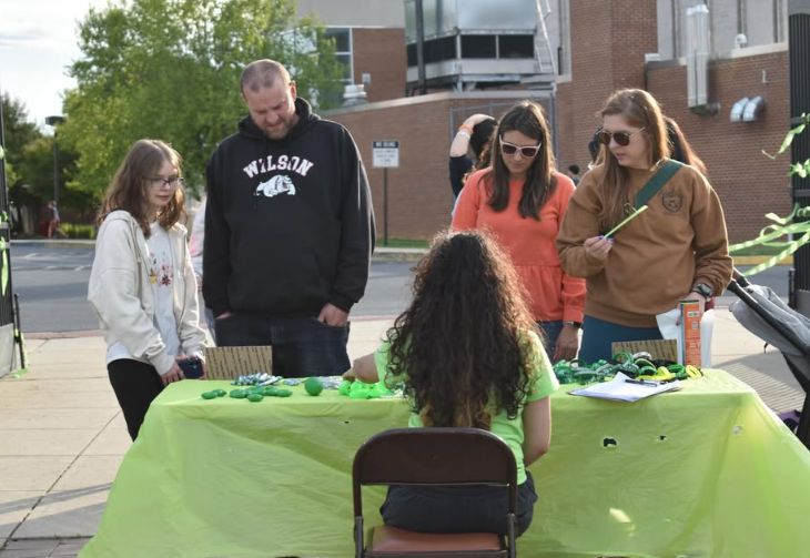 people checking into event at a table with a girl sitting at it