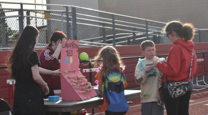 girls running a stand for a ring toss with kids trying it out