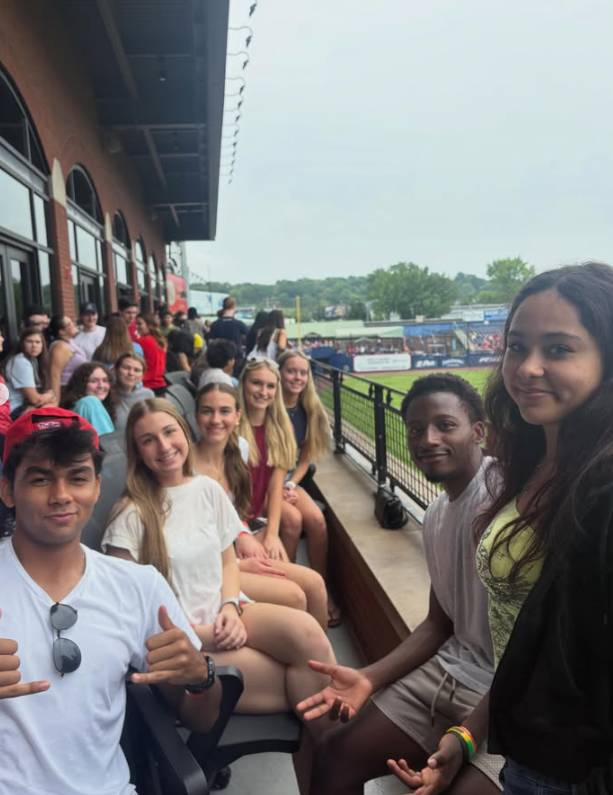 group of students sitting outside watching baseball game