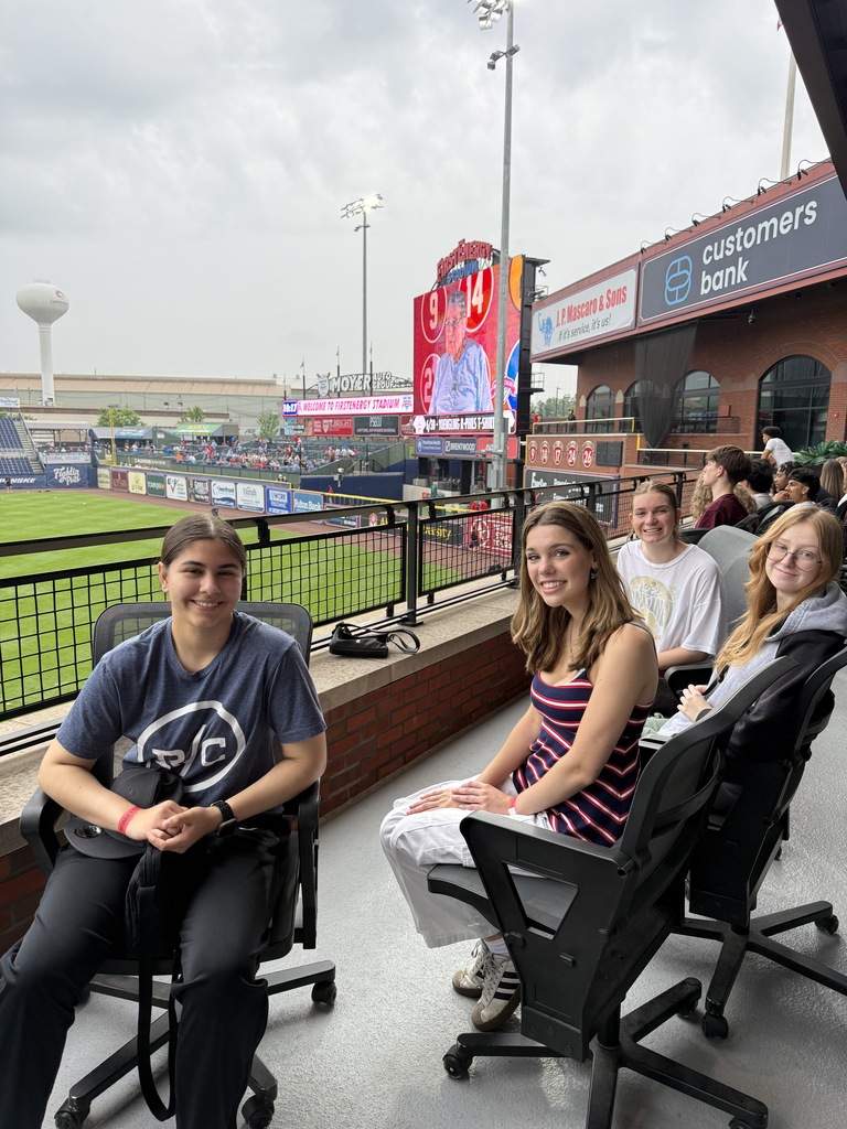 students smiling with baseball  field in the background