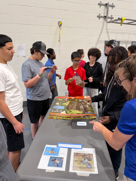 students standing around a table holding a bird wing