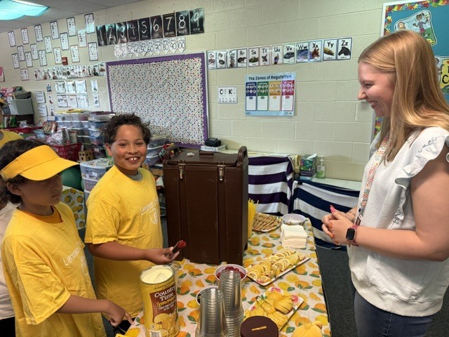 student smiling at camera serving teacher lemonade