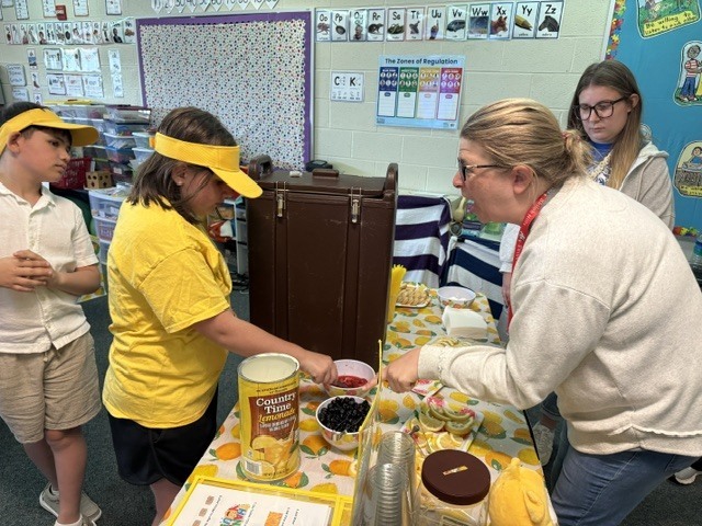 student serving lemonade to a teacher
