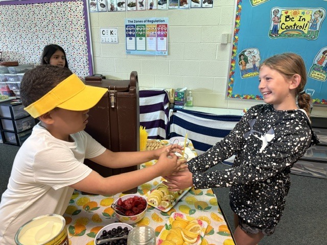 student serving lemonade to another student