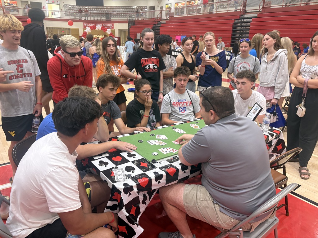students standing around table playing card game
