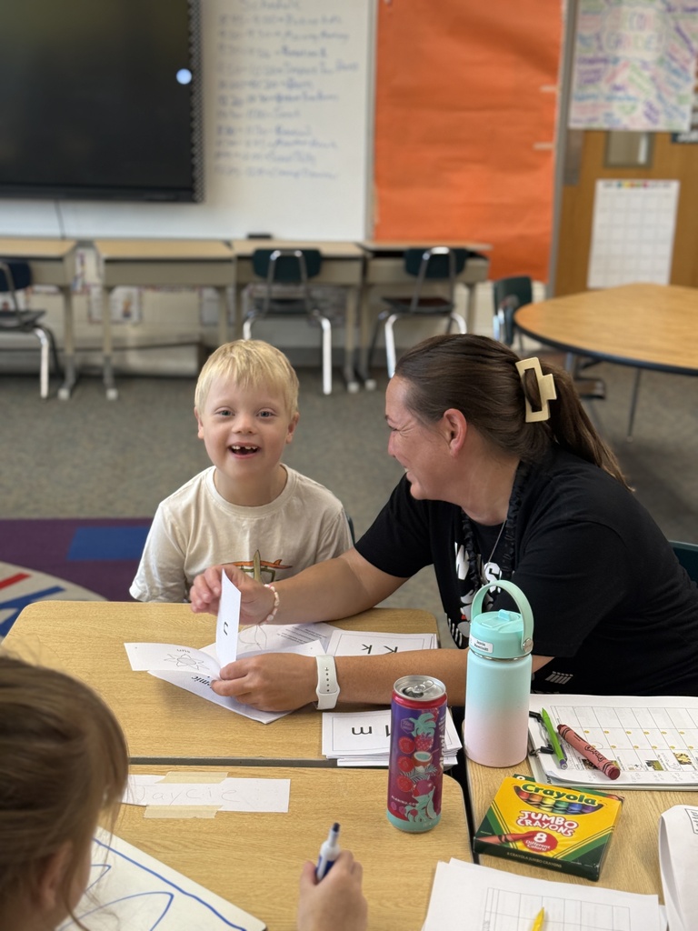 student smiling at camera and women smiling at boy