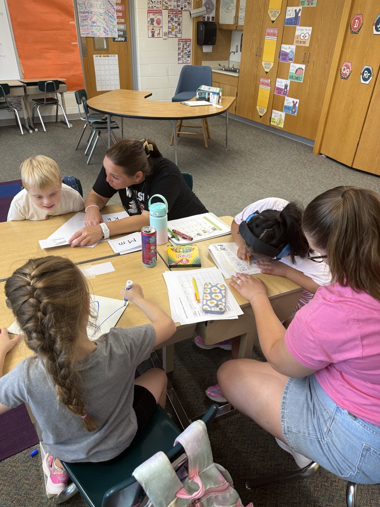 group of students a table doing different activities on paper