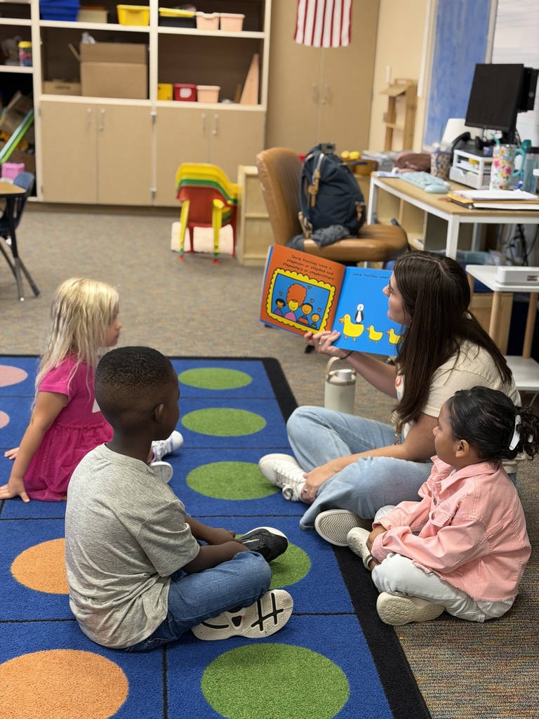teacher reading book to students on carpet