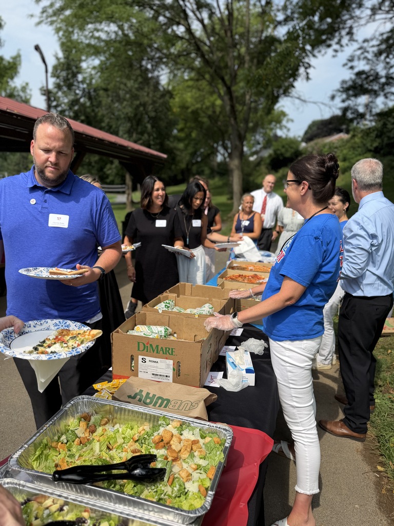 people serving sandwhiches and salad to line of food