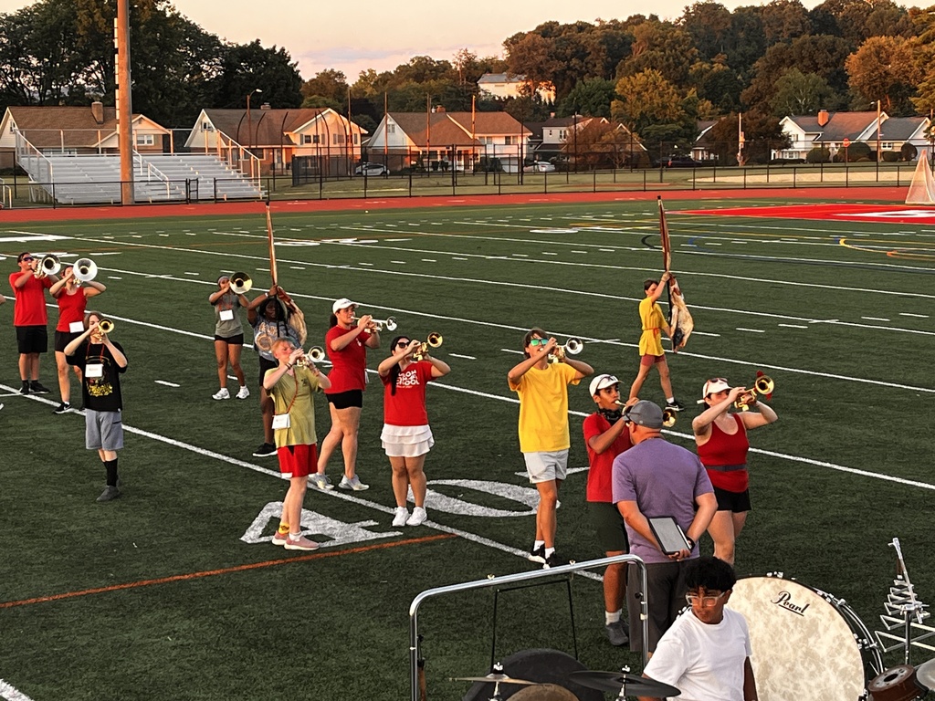 students playing instruments on the field at sunset