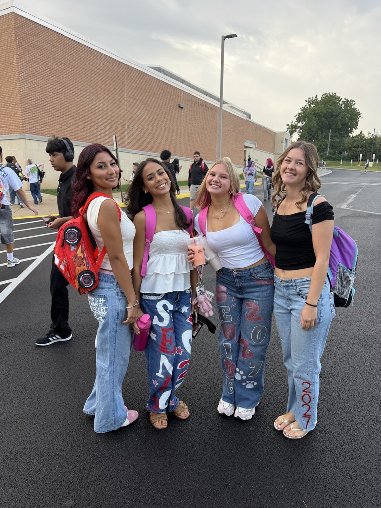 girls smiling at camera in painted jeans that say senior