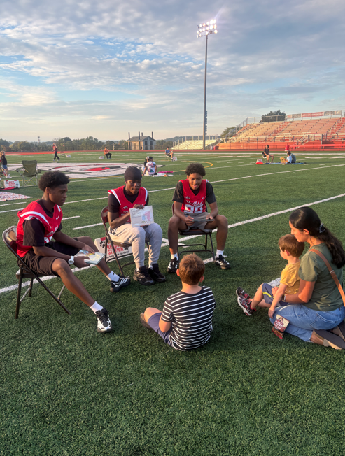 football players reading to students