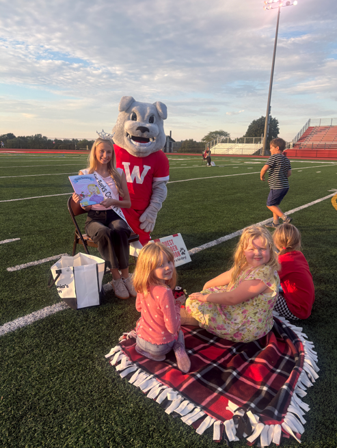 students smiling with bulldog and pagent queen