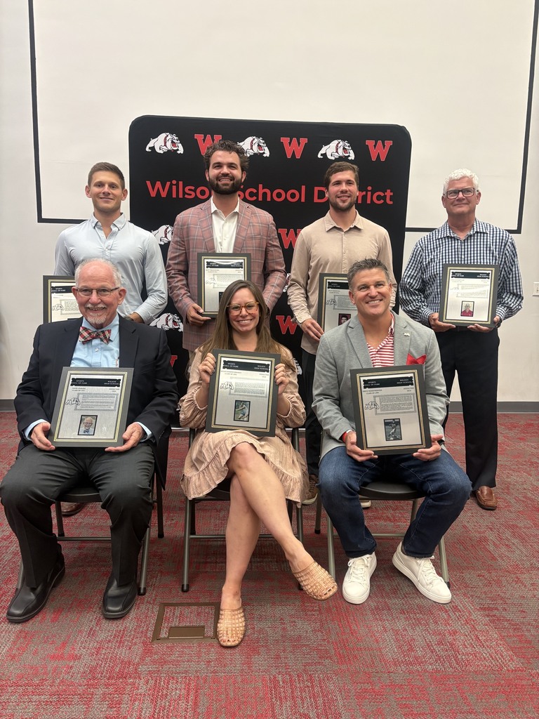 7 people standing in front of wilson backdrop holding plaques