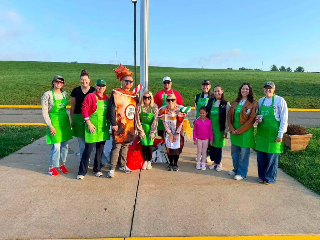 group of staff members standing outside in their aprons and uniforms