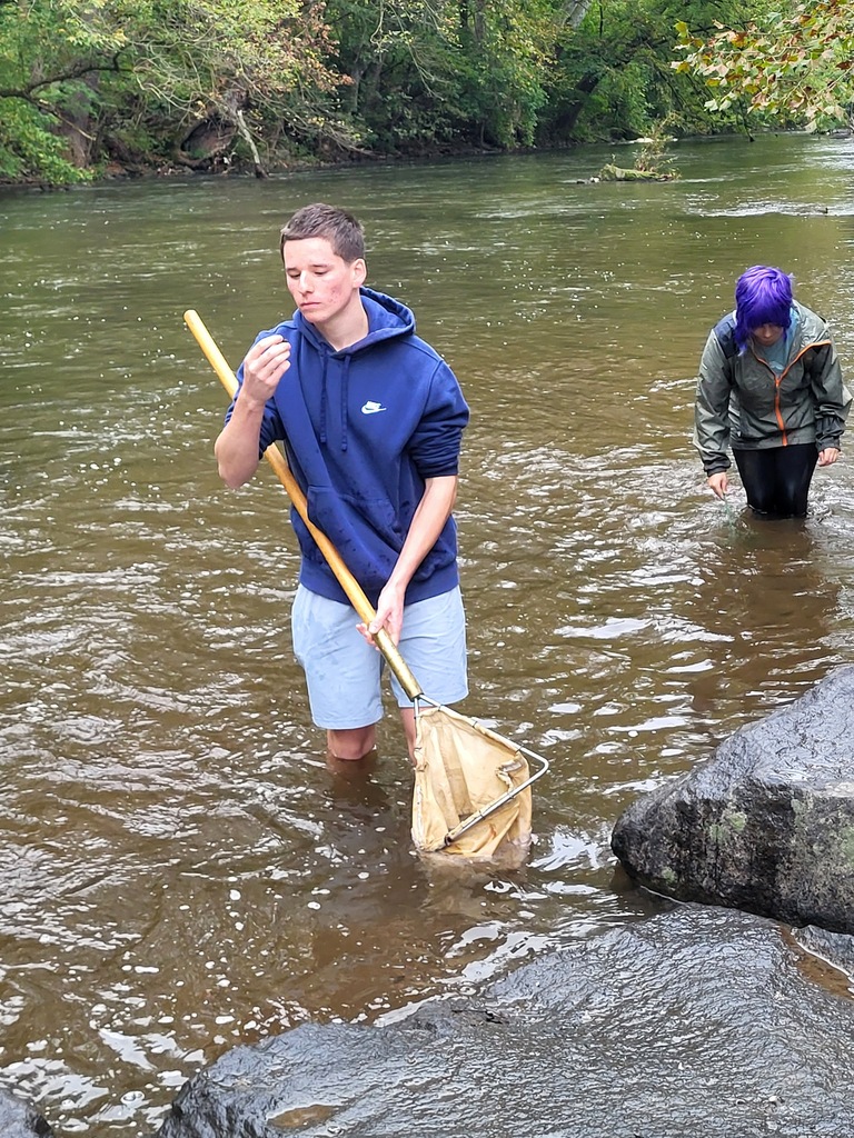 student in creek with net