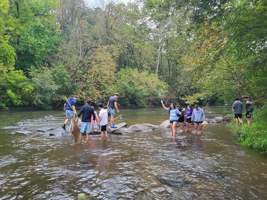 students in creek with shovels