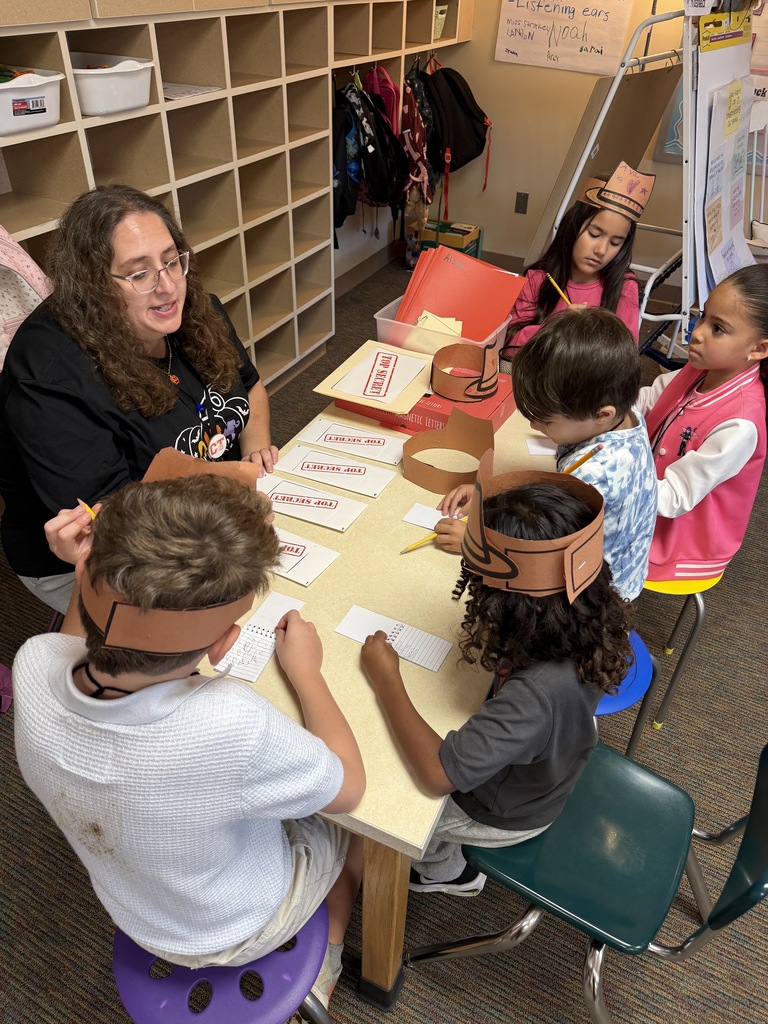 students sitting at a table with teacher and enevlopes that say top secret