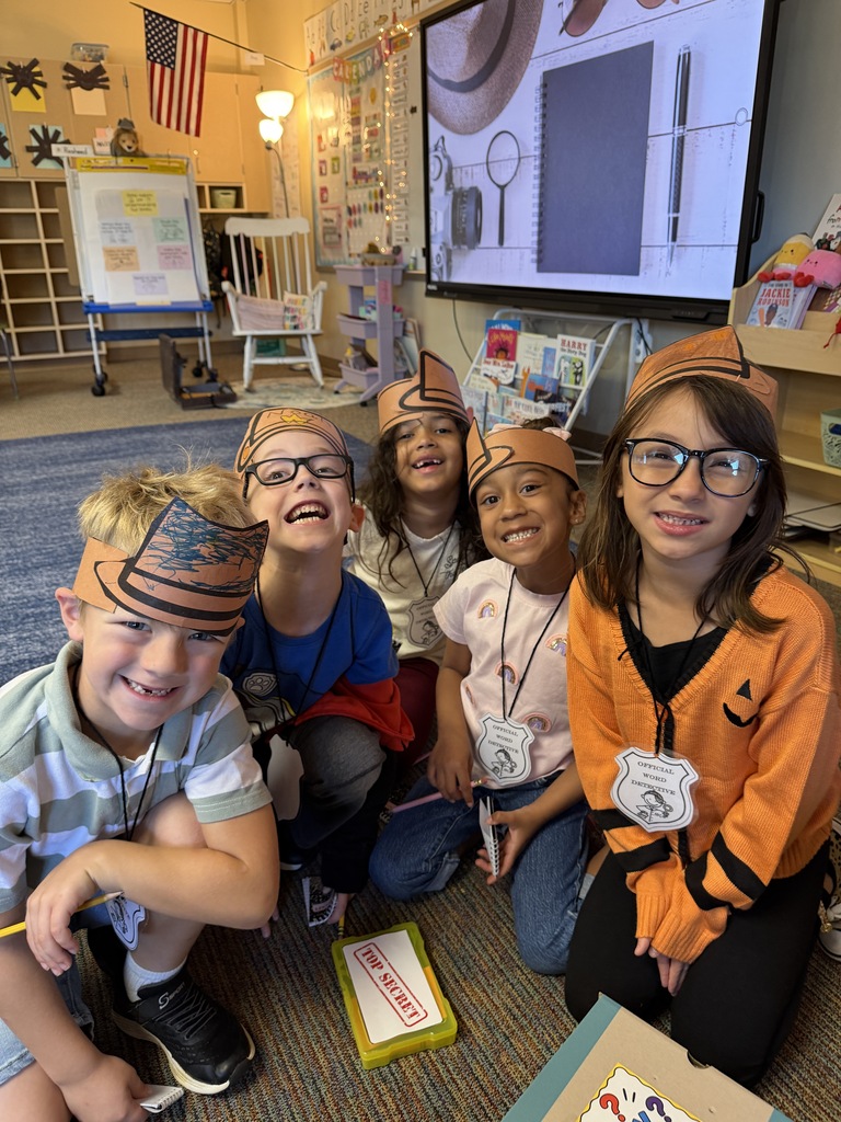 students smiling at camera with detective hats on