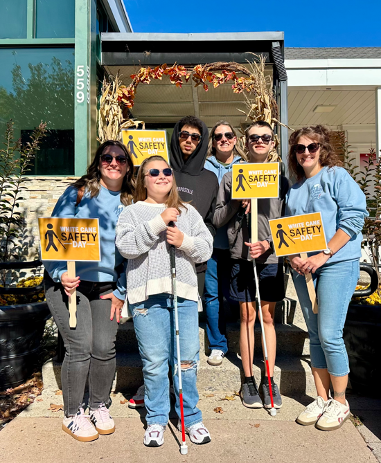 group of people holding signs that says white cane safety day and students with white canes