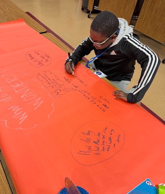 student writing on bright orange paper