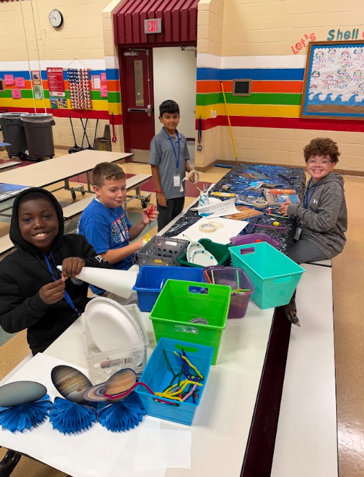 students sitting at caferia table making crafts iwth scissors and paper products