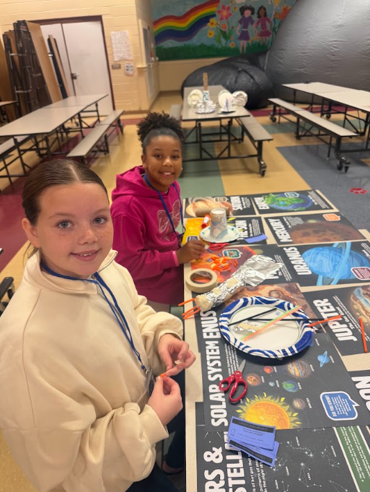students sittting at cafeteria table smiling at camera