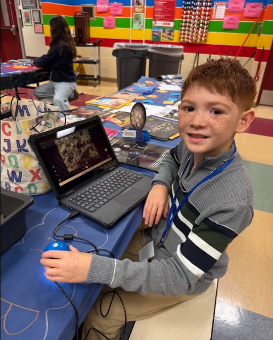 student sitting at cafeteria table with chromebook
