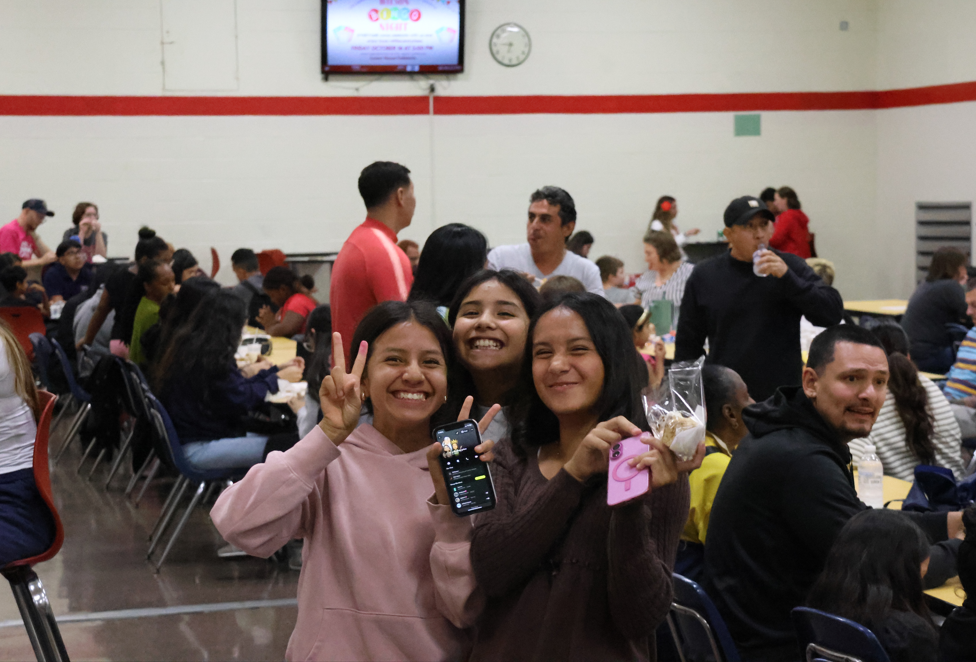 three girls smiling at camera with peace sign fingers