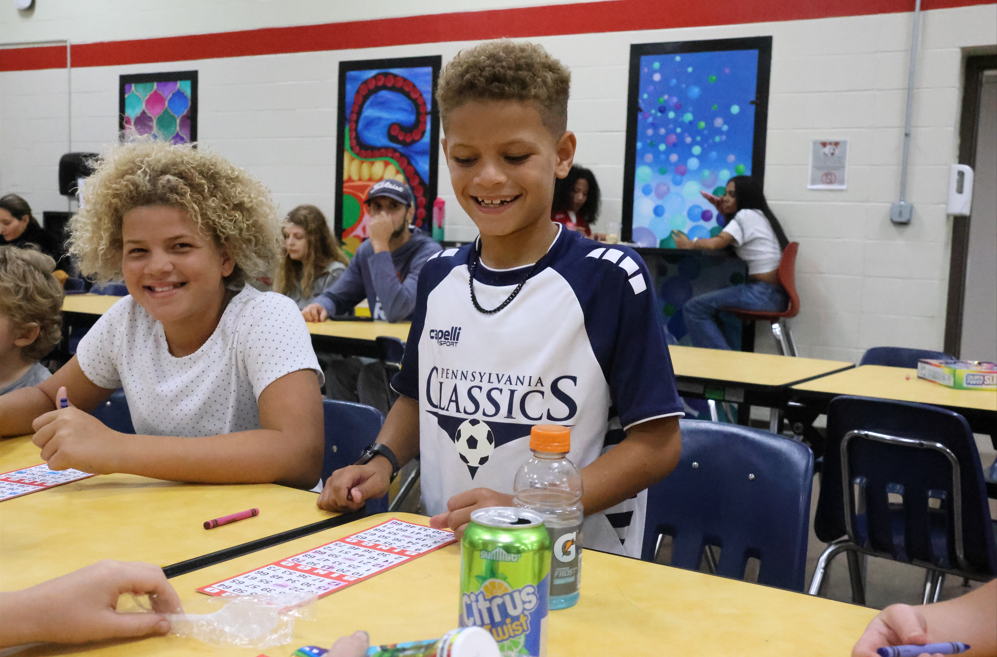 children smiling and playing bingo in the cafeteria