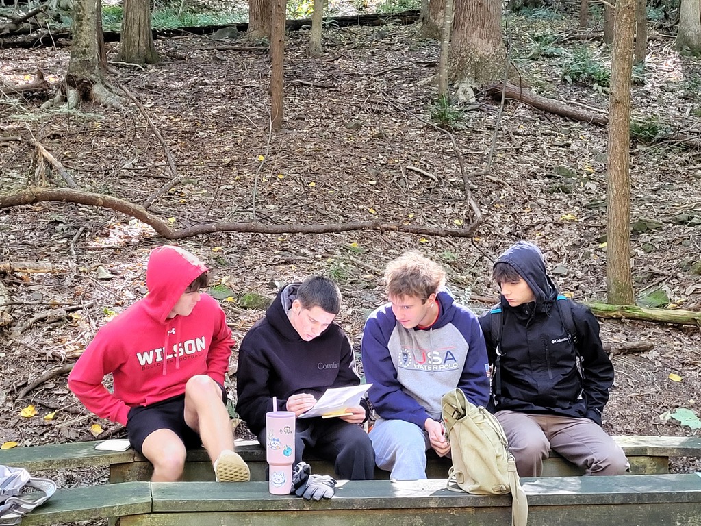 students sitting on bench wiritng on paper