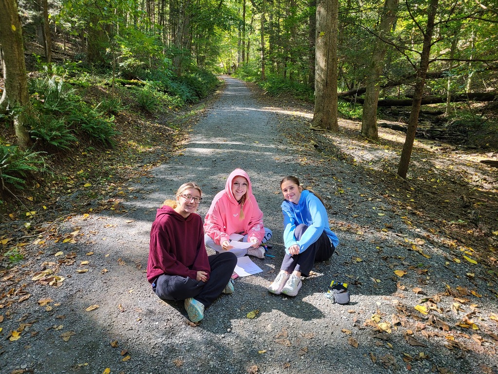three girls sitting on path in forest