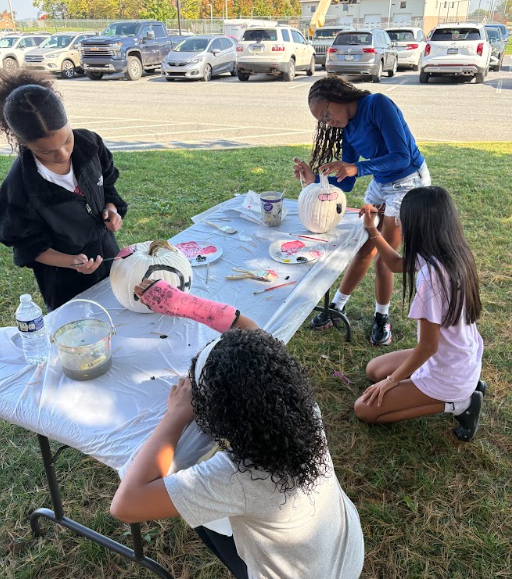 students painting pumpkins outside