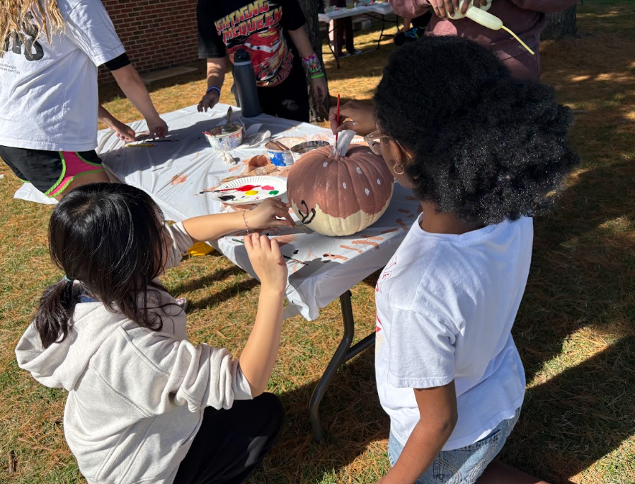 two students painting one pumpkin